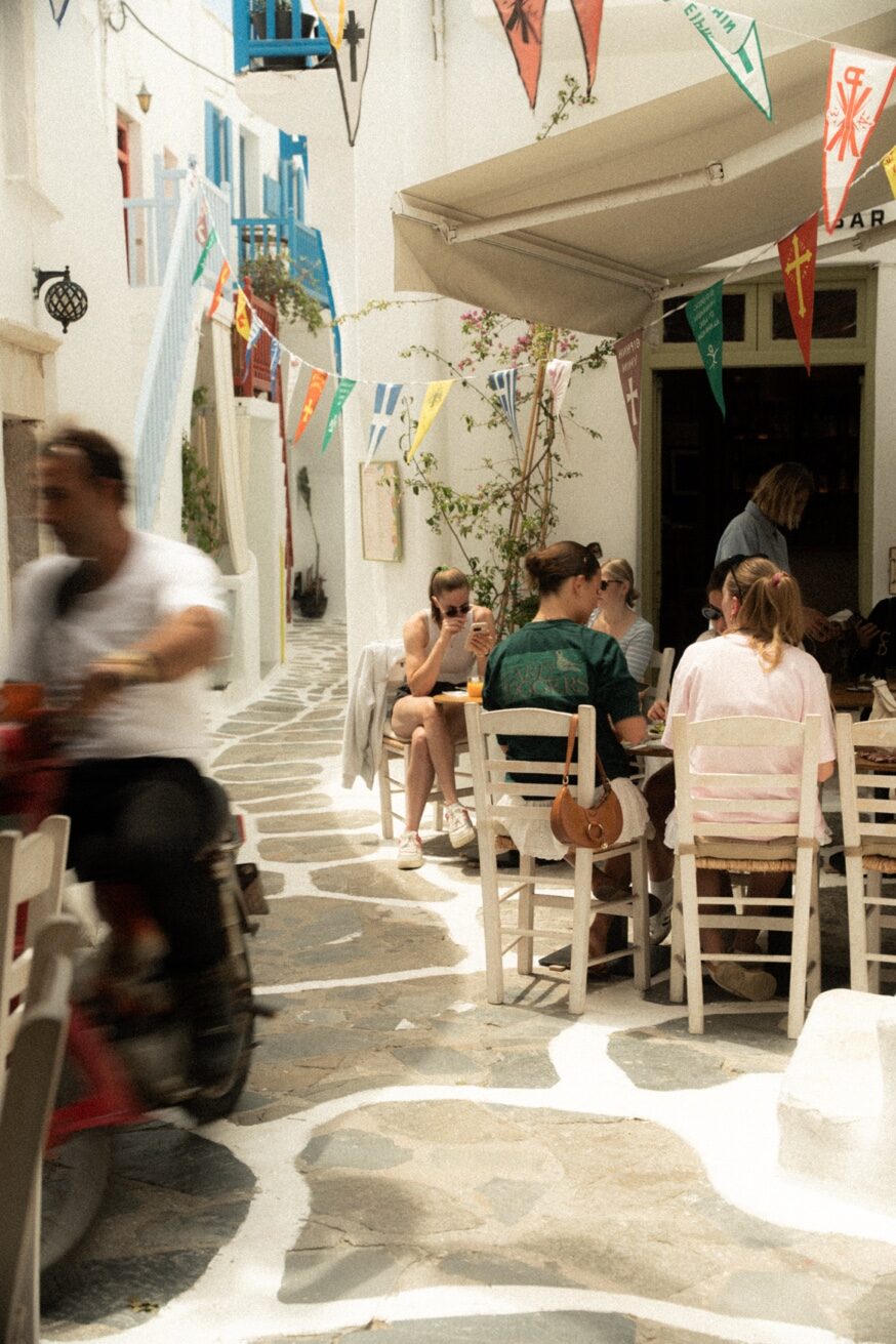 Couple dining at Mykonos Brunch Club outdoor terrace under the Pūblico sign