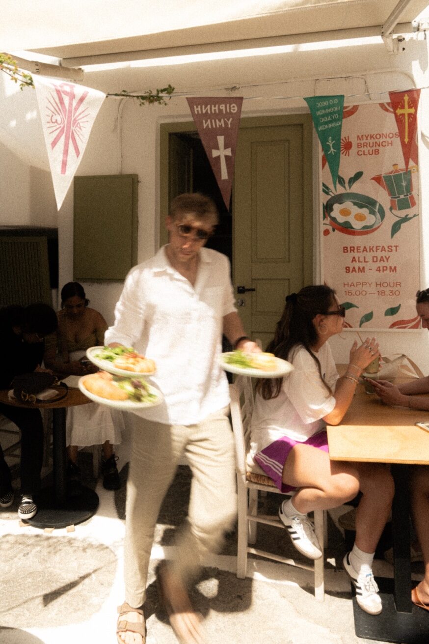 Owner taking orders from guests at Mykonos Brunch Club Mykonos Town terrace