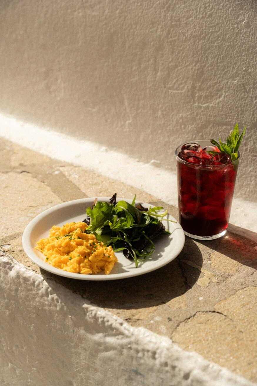 Scrambled eggs and cold drink on Mykonos cobblestones at Mykonos Brunch Club